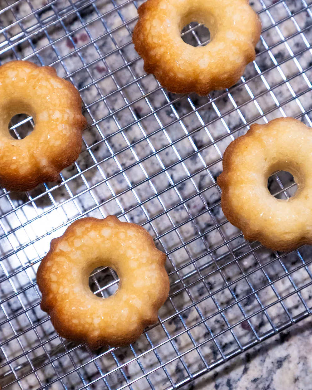 Freshly baked mini bundt cakes cooling upside down on a wire rack.