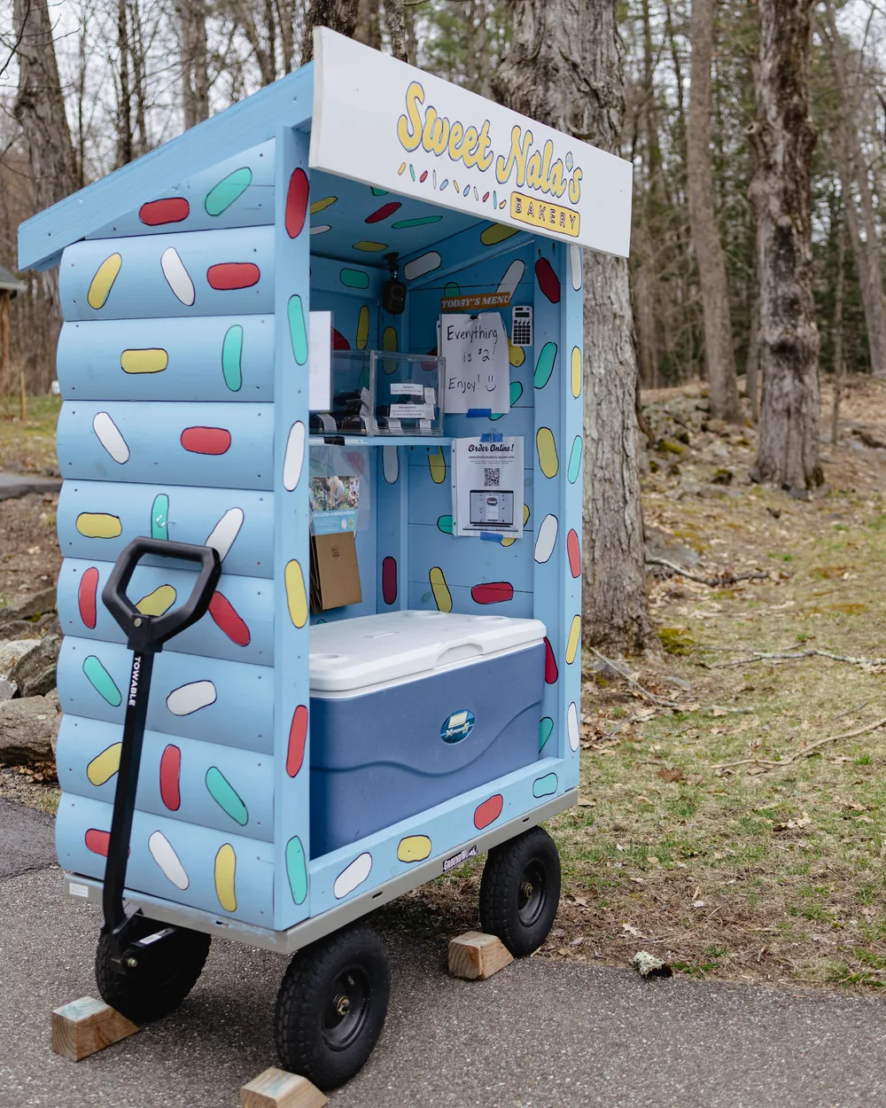 The bakery cart from the side, showing hand-painted sprinkles down the panels and its wagon wheels.