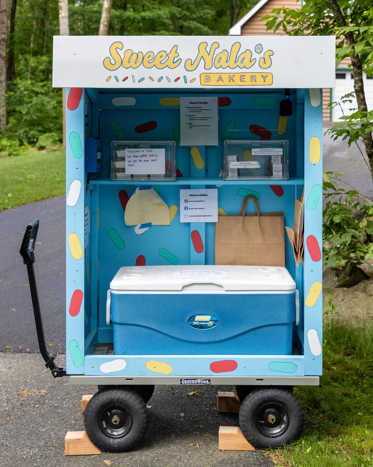 The Sweet Nala's Bakery cart: a light blue wooden cart hand-painted with sprinkles, with a white roof sign reading Sweet Nala's Bakery.