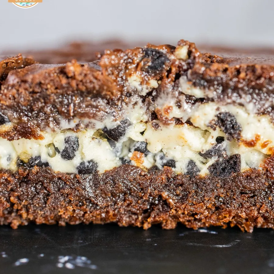 A cookies and cream brownie cut in half, showing a cheesecake and cookie layer through the middle.