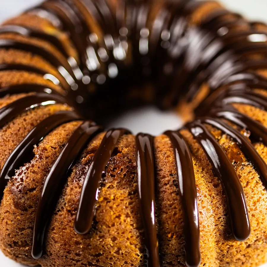 A full size butterfinger bundt cake with chocolate drizzled over the top.
