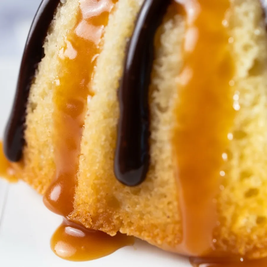 A close view of caramel and chocolate running down a Twix bundt cake.